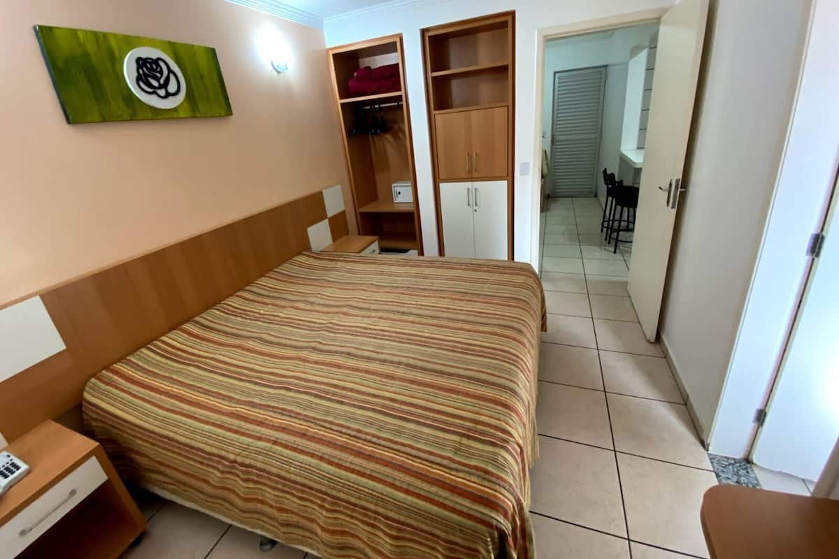 Une chambre à coucher comprenant un lit, une table de chevet, une armoire et un bureau avec une chaise.