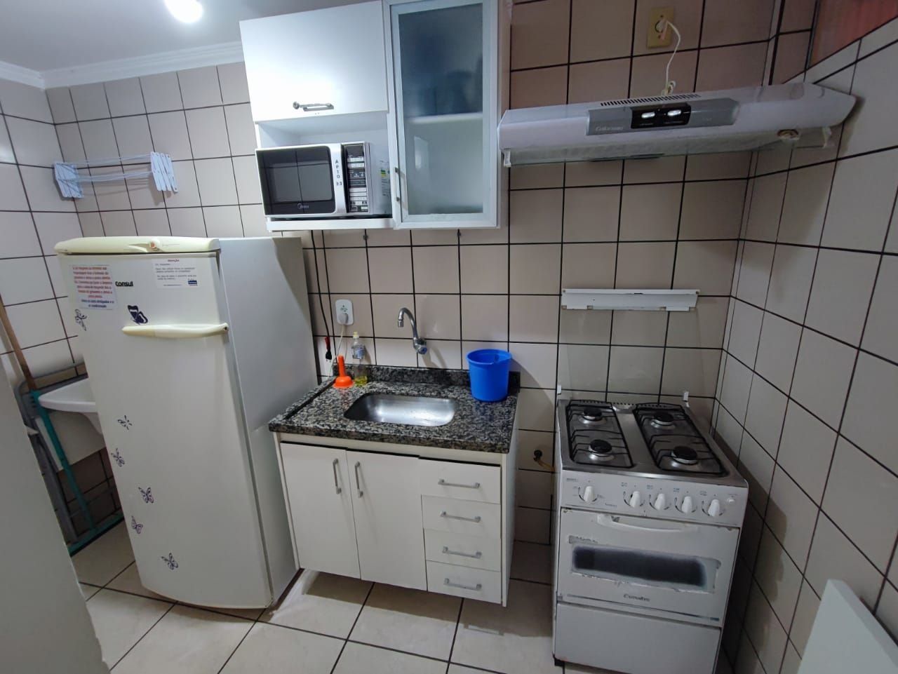 Una cocina compacta equipada con refrigerador, microondas, pileta y estufa.