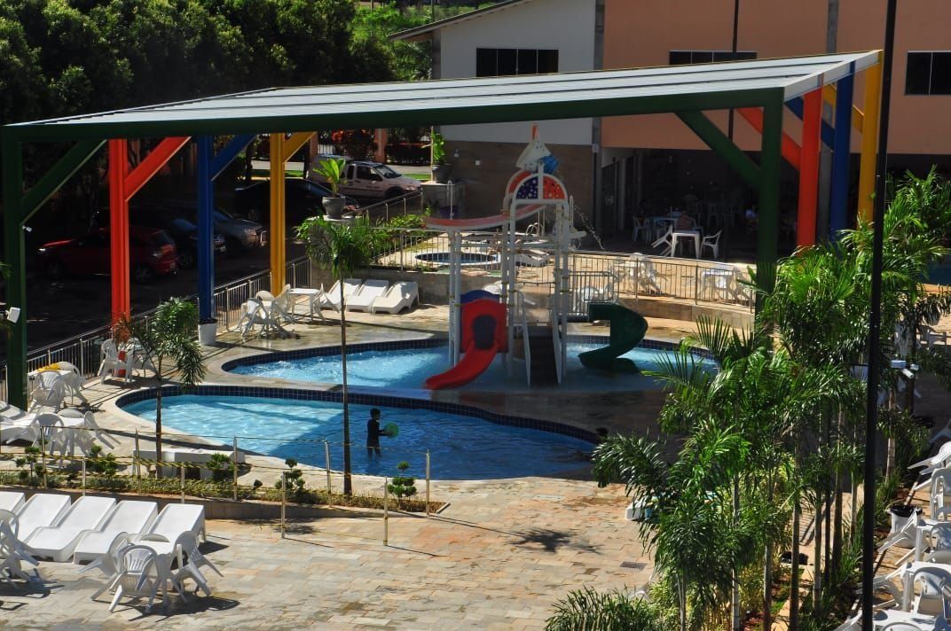 A pool area with a slide, lounge chairs, and a covered seating area.