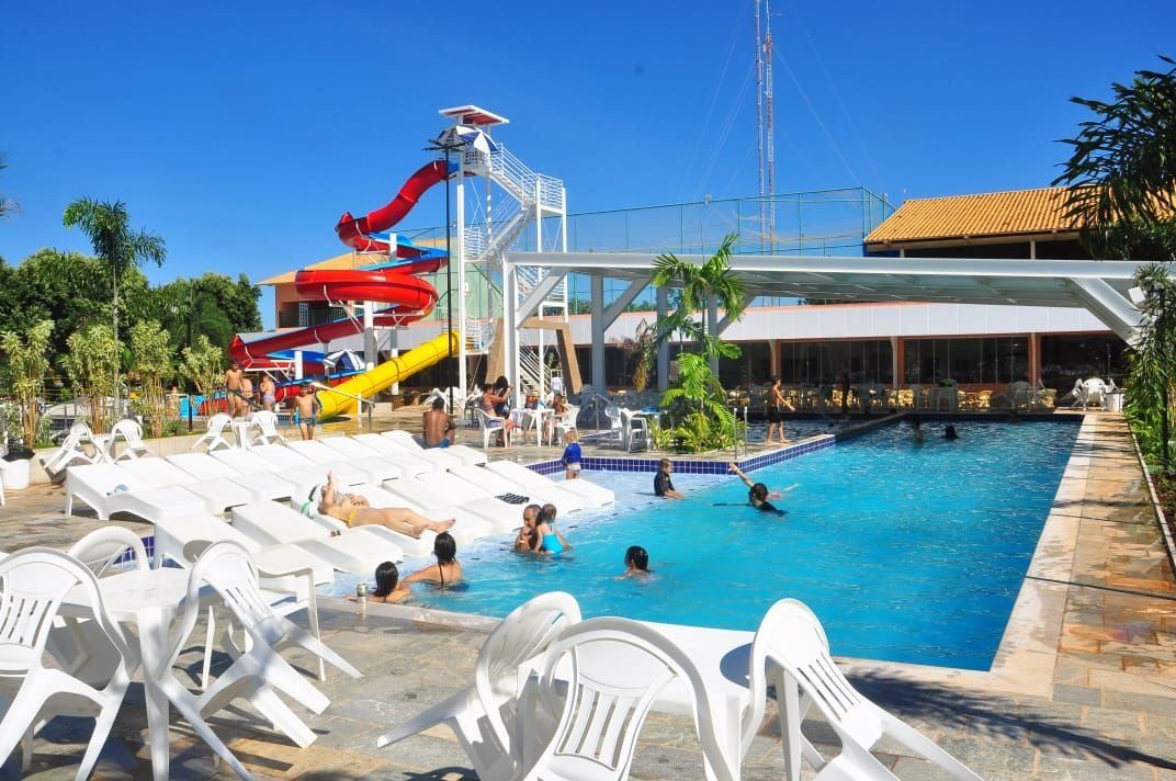 A swimming pool with lounge chairs, a water slide, and a covered area with a view of the pool.