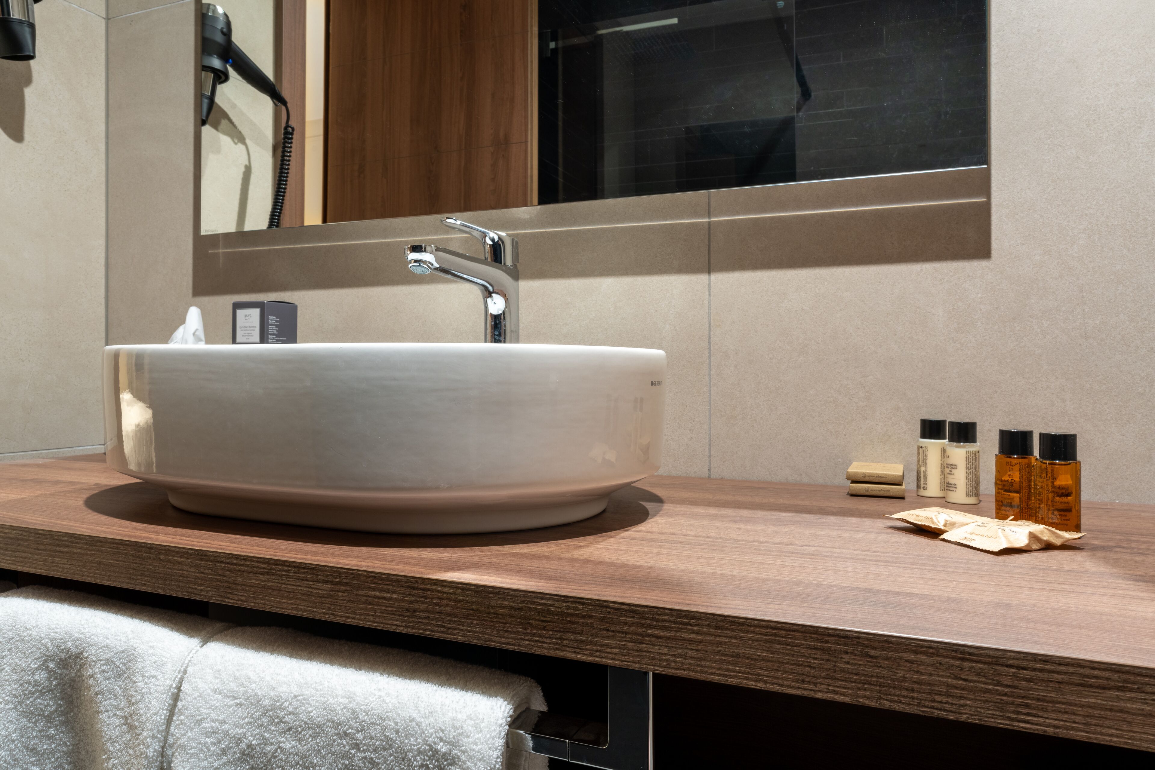 Un baño moderno con un lavabo de pedestal grande, un espejo y artículos de tocador sobre el mostrador.
