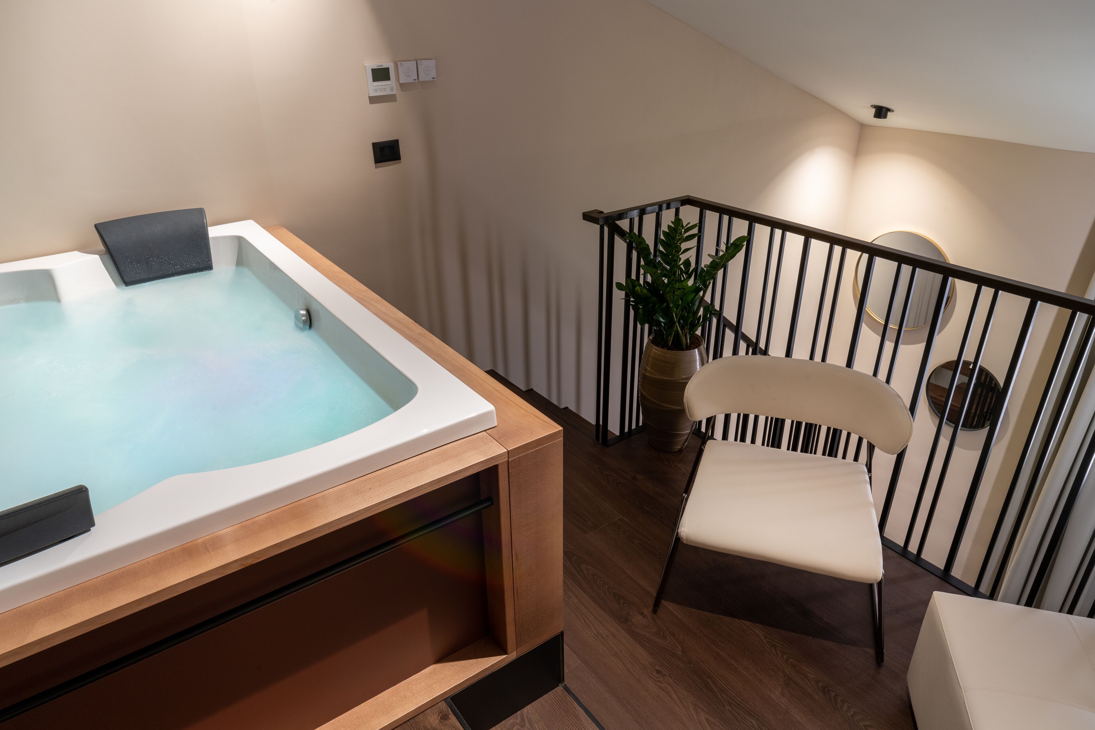A modern bathroom with a bathtub, a wooden bench, and a chair.