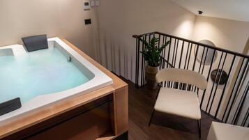 A modern bathroom with a bathtub, a wooden bench, and a chair.
