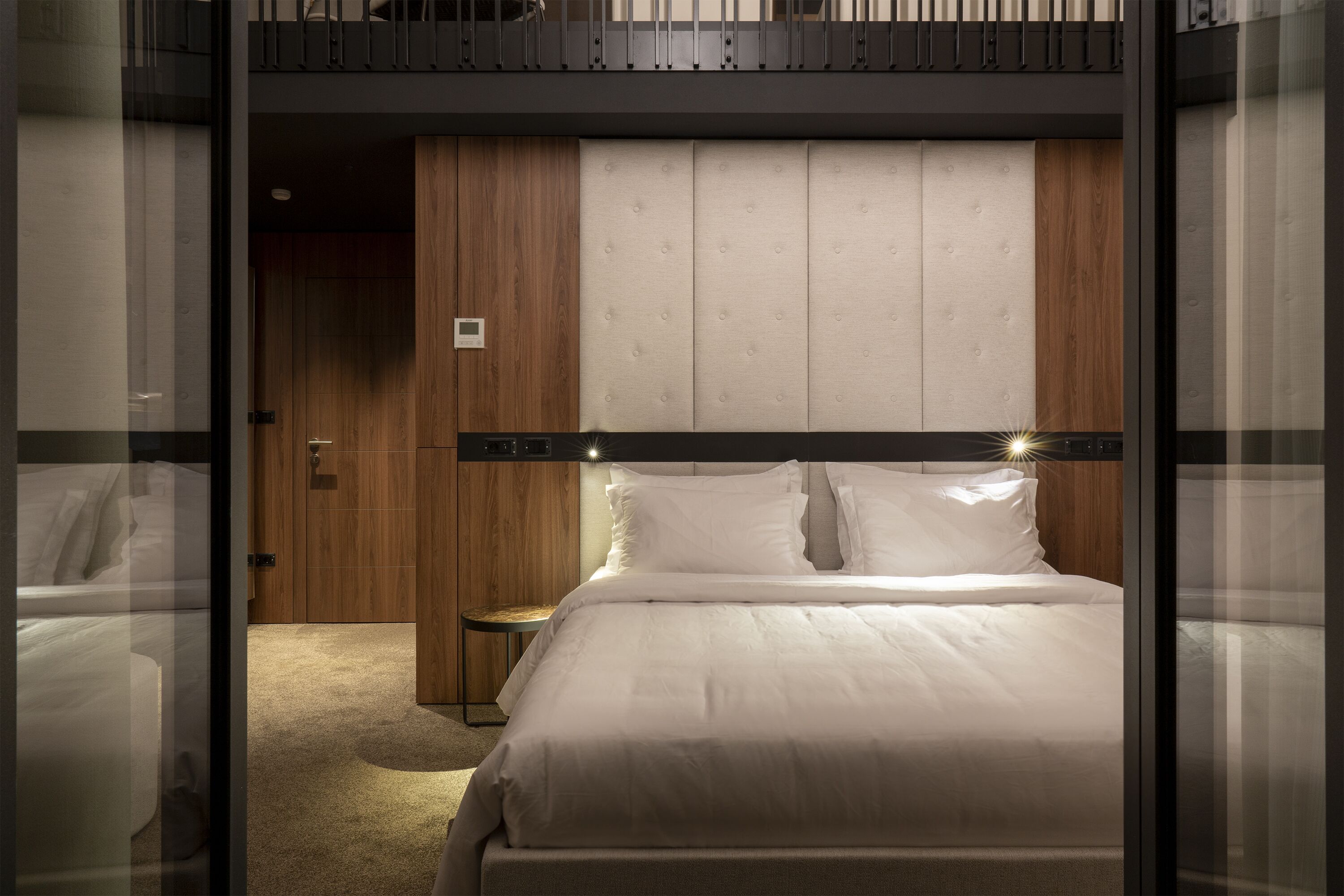 Una habitación de hotel moderna con una cama grande, un armario de madera y una mesita pequeña.