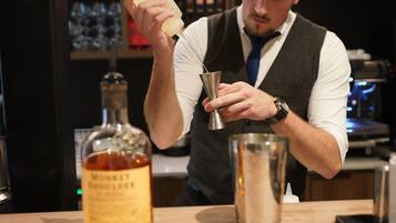 A bartender preparing a drink with a bottle of whiskey and a metal shaker.