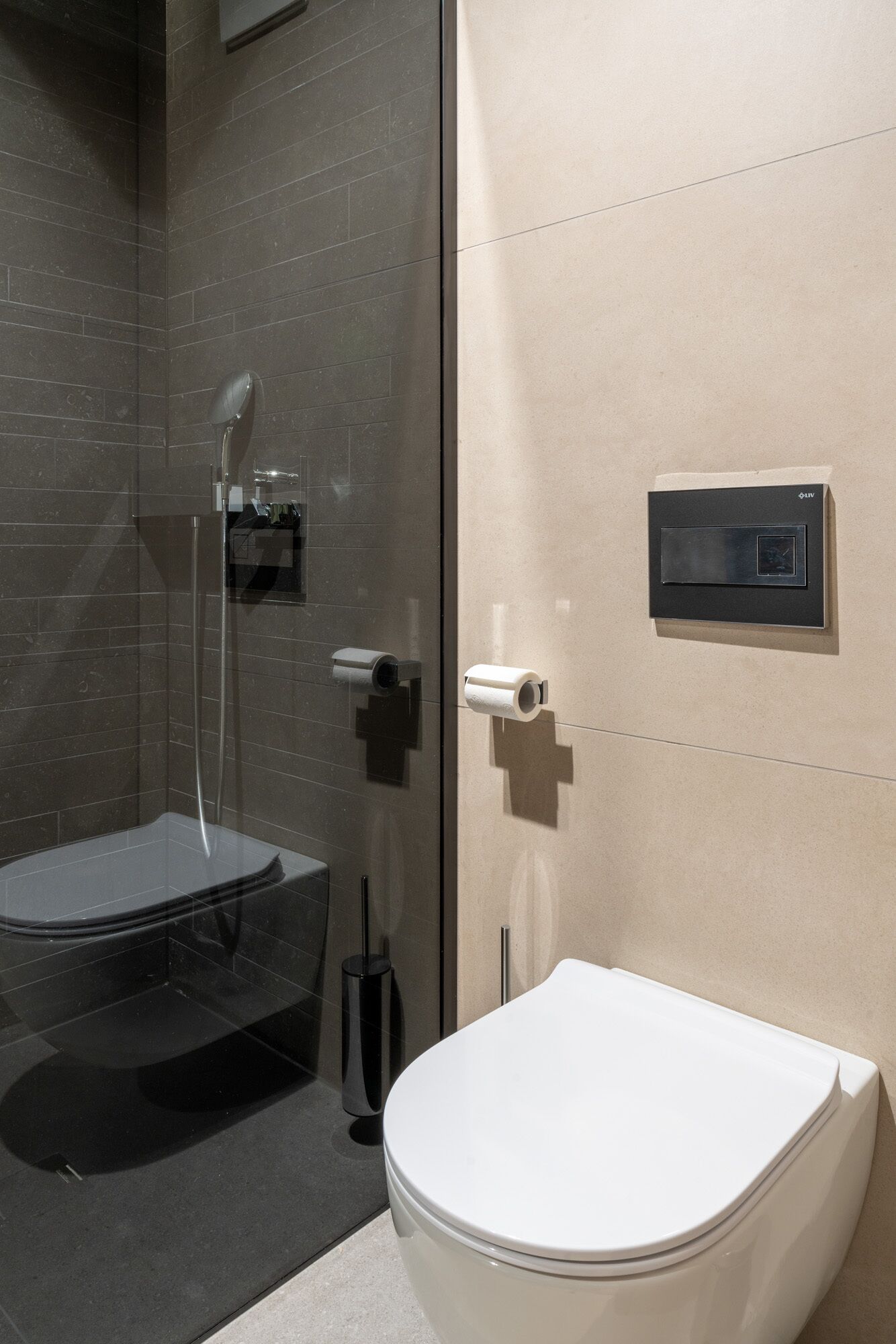 A modern bathroom with a glass-enclosed shower, a toilet, and a wall-mounted toilet paper holder.