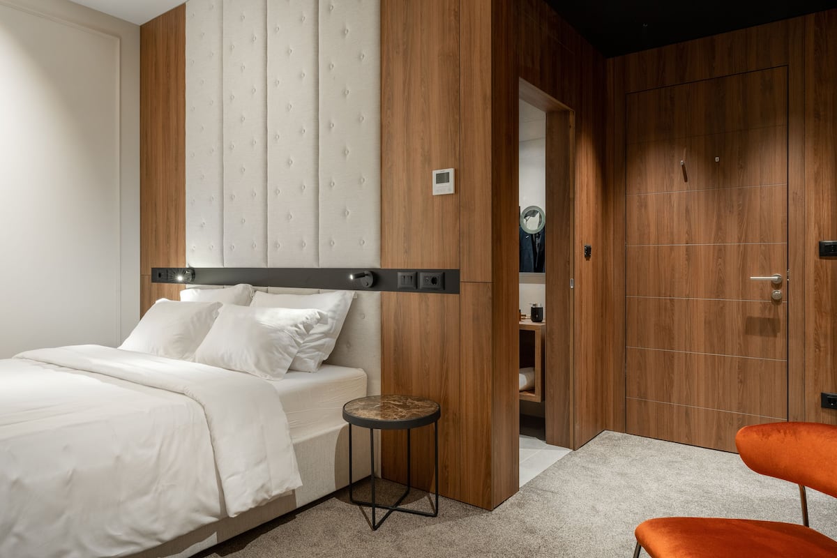 Quarto moderno com cama, uma mesinha redonda e um guarda-roupa de madeira.