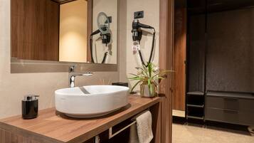 A modern bathroom with a large mirror, a white sink, a hairdryer, and a towel rack.