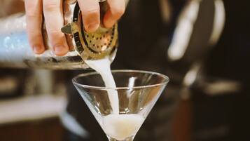 Una persona sirviendo un líquido en una copa de martini.