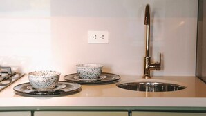 A kitchen with two speckled bowls on a round tray, a stainless steel sink, and a gold faucet. - Cabaña Vacacional el Peñol con Jacuzzi (Guatapé)