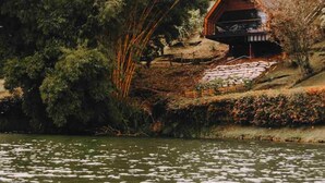 A cabin with a sloped roof, surrounded by dense trees and a stone pathway leading to it. - Cabaña Vacacional el Peñol con Jacuzzi (Guatapé)