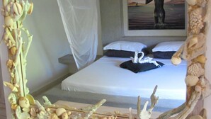 A bedroom with a bed, white bedding, a painting of two people on the wall, and a canopy over the bed. - Stunning 3-bed Villa in Watamu (Watamu)