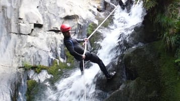 A person rappelling down a rocky waterfall.