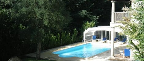 Una piscina al aire libre de temporada, sillones reclinables de piscina