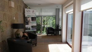 A modern living room with a sofa, armchair, and a coffee table. There is a poster on the wall and a window providing natural light. - Hotel Rural Quinta de Novais (Arouca)