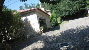 A stone building with a tiled roof, a stone entrance, and potted plants nearby.