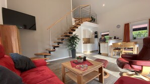A modern living room with a red sofa, a wooden coffee table, and a staircase leading to an upper level. - "Little uncle" (Wiefelstede)