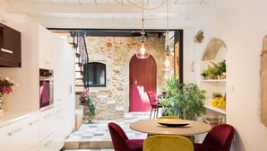 Une cuisine moderne avec un mur en pierre, une porte rouge et un coin repas comprenant deux chaises rouges et une chaise jaune.