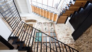 Un escalier avec une rampe en métal menant à un palier doté d’un plancher en bois et d’une fenêtre avec des volets.