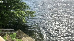Une jetée en bois s’étendant sur une étendue d’eau, où se reflètent les arbres et le feuillage.