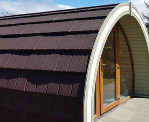 A building with a dark shingle roof and a curved entrance with glass doors.