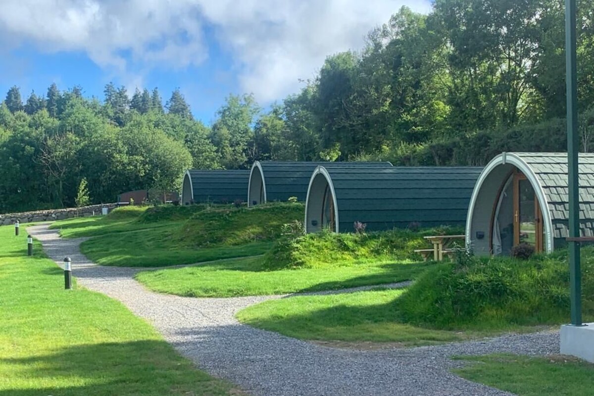 A row of green-roofed, semi-open structures with a gravel path leading to them.