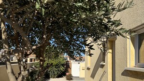 A residential building with a gravel driveway, a small patio area, and a tree providing shade. - FULLY AIR-CONDITIONED, COMFORTABLE HOUSE WITH PRIVATE POOL (Sauvian)