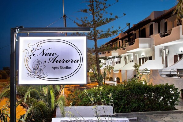 Señal de 'New Aurora Apts Studios' con vista a un conjunto residencial.