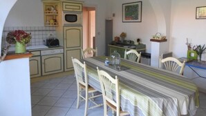 A kitchen with a dining table, chairs, and a microwave. - Landes house 10 min from the beach, 5min from the cycle path and forest (Mimizan)