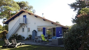 A two-story house with a patio, outdoor seating, and a staircase leading to the upper floor. - Landes house 10 min from the beach, 5min from the cycle path and forest (Mimizan)