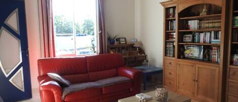 A living room with a red sofa, a wooden bookshelf, a coffee table, and a chandelier.