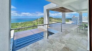 A balcony with a clear view of the ocean and greenery.