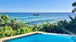 A clear view of a swimming pool with a view of the sea and a boat in the distance.