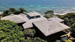 A large, modern house with multiple roof sections and a view of the ocean.