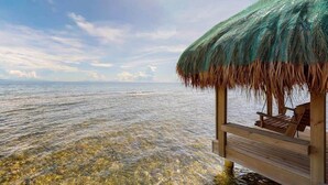A wooden deck with a thatched roof, overlooking a clear sea. - Villa con Vista @ Calabash Bight, Roatan. (Oakridge)