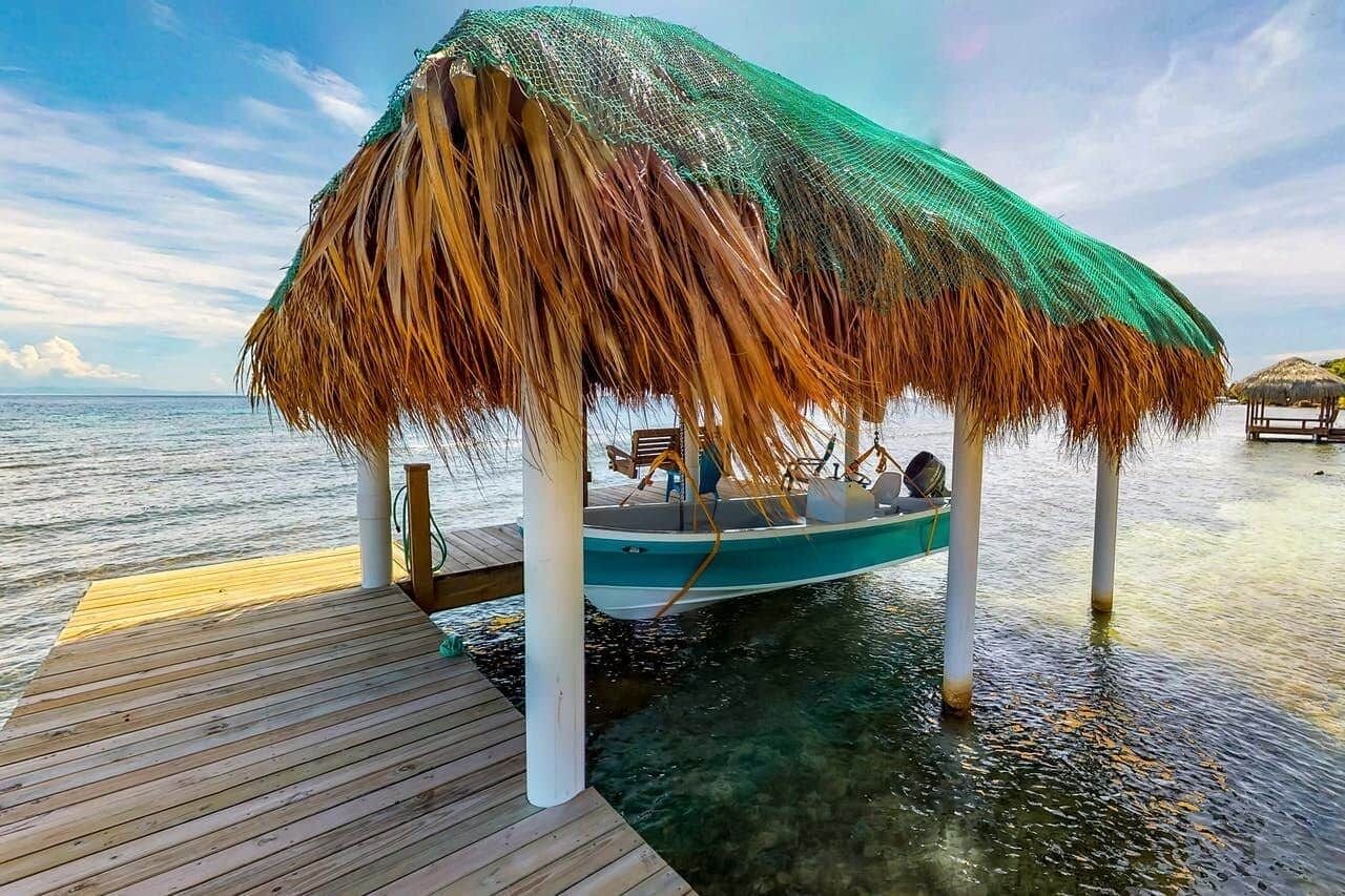 A boat docked on a wooden pier with a thatched roof structure.