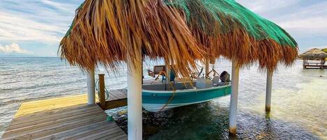 A boat docked on a wooden pier with a thatched roof structure.