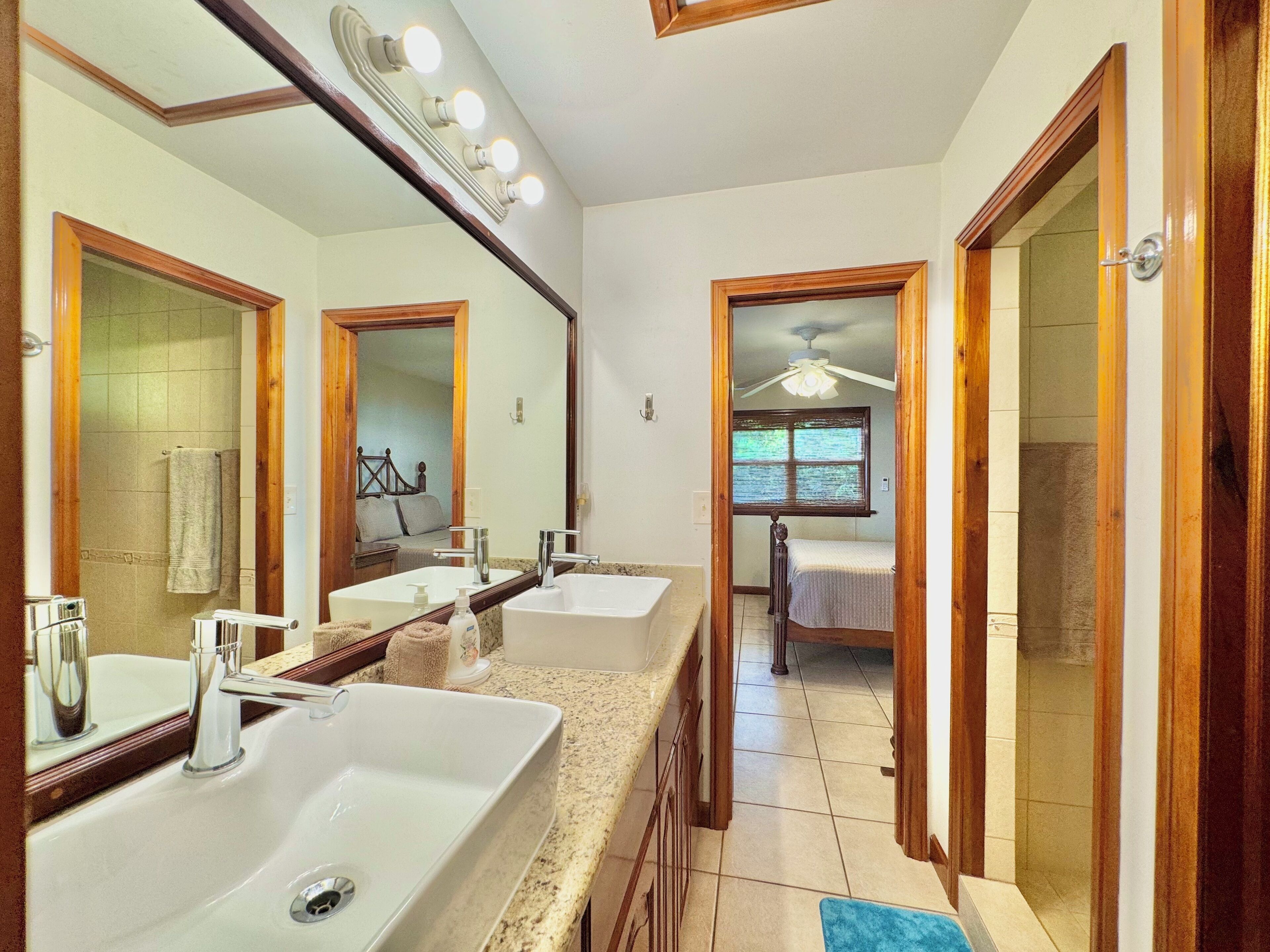 Un baño con dos lavamanos, un espejo grande y una zona de ducha.