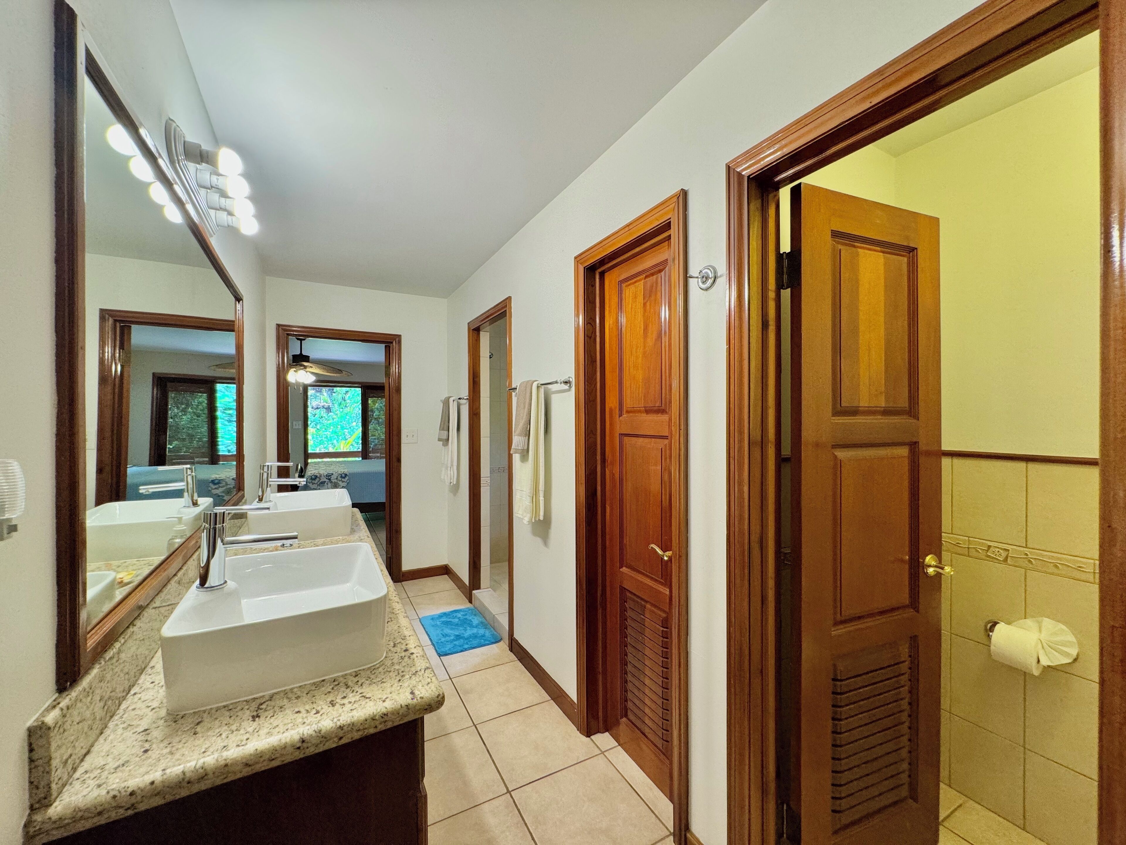 Un baño con lavamanos doble, espejo y ducha.
