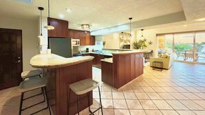 A modern kitchen with a bar area, a dining space, and a view of the outdoors. - Coral Sand 10, Condos #1 & 5 @ West Bay Beach (West Bay)