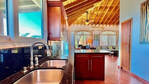 Una cocina moderna con una isla grande, electrodomésticos de acero inoxidable y techo de madera.