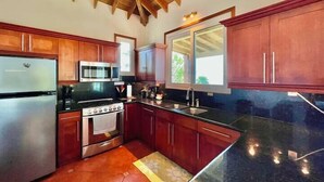 Una cocina con armarios de madera, un refrigerador de acero inoxidable, un microondas, una estufa y un lavaplatos.
