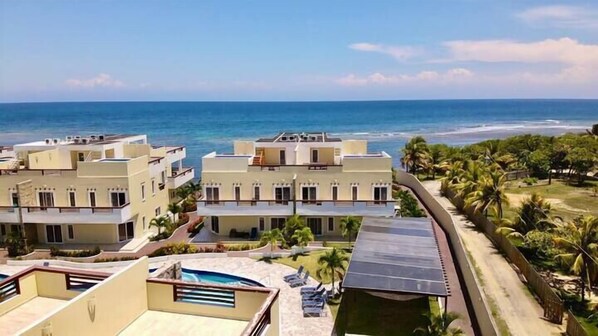 A coastal hotel with multiple buildings, a pool, and a view of the ocean.