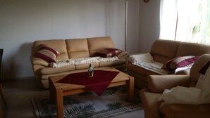 A living room with a beige sofa, a wooden coffee table, and a patterned rug. - House Bergrose (Busenborn)