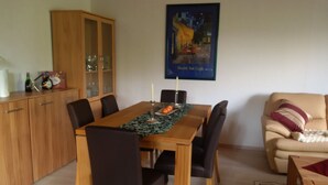 A dining area with a wooden table, black chairs, a cabinet, and a poster on the wall. - House Bergrose (Busenborn)