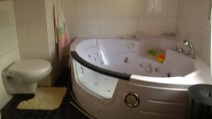 A bathroom with a bathtub, toilet, and a towel rack. - House Bergrose (Busenborn)