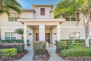 A two-story building with a covered entrance, numbered doors, and a well-maintained garden with various plants and shrubs. - In the Heart of Kissimmee - Storey Lake Resort - 4bd/3ba Pool Townhome #4sl4857 (Kissimmee)