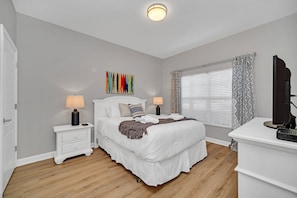 A bedroom with a bed, bedside tables, a lamp, a TV, and a window with blinds. - In the Heart of Kissimmee - Storey Lake Resort - 4bd/3ba Pool Townhome #4sl4857 (Kissimmee)