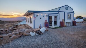 A white building with a blue roof, a gravel driveway, and a dog in the background. - The Prickly Pear: Experience Arizona Agritourism (Kingman)