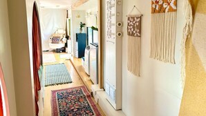 A narrow hallway with a wooden floor, a patterned rug, and a macrame wall hanging. - The Prickly Pear: Experience Arizona Agritourism (Kingman)